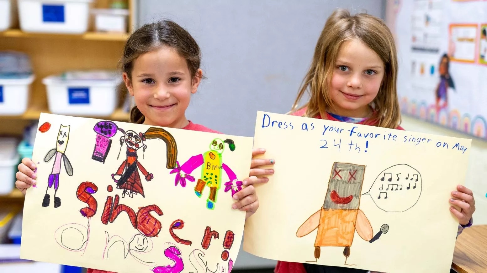 Two grade school students hold up posters they'd drawn up promoting singer dress up.